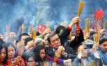 Worshippers hold incense sticks aloft as they make offerings and pray on the second day of the Lunar New Year, while one man pauses for a quick photo at a packed Wong Tai Sin Temple in Kowloon. The popular temple is home to three religions - Taoism, Buddhism and Confucianism. Photo: Edward Wong