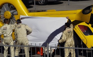 Fernando Alonso is shielded by teammates and medical staff as he is carried by stretcher to the evacuation helicopter. Photo: AFP