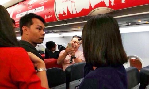 An angry passenger glares along the plane, while another records the incident on his mobile phone